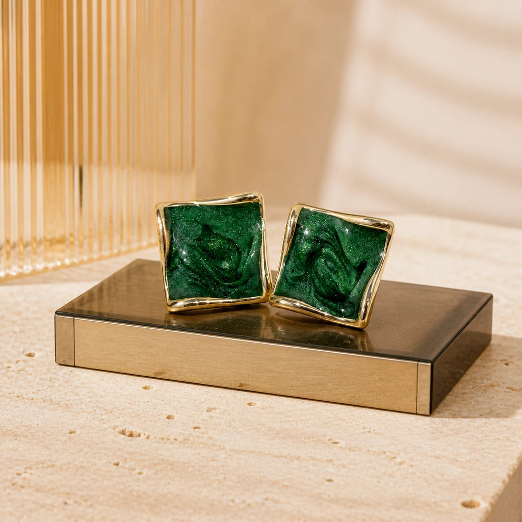 Deep green square stud earrings in gold on modern retro display plinth