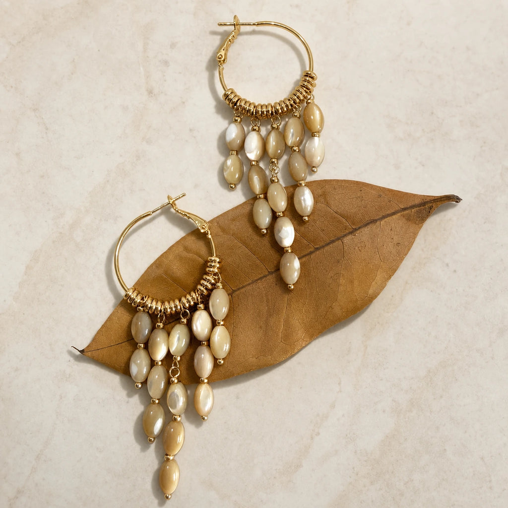 Bohemian pearl tassel drop earrings in gold styled on leaf