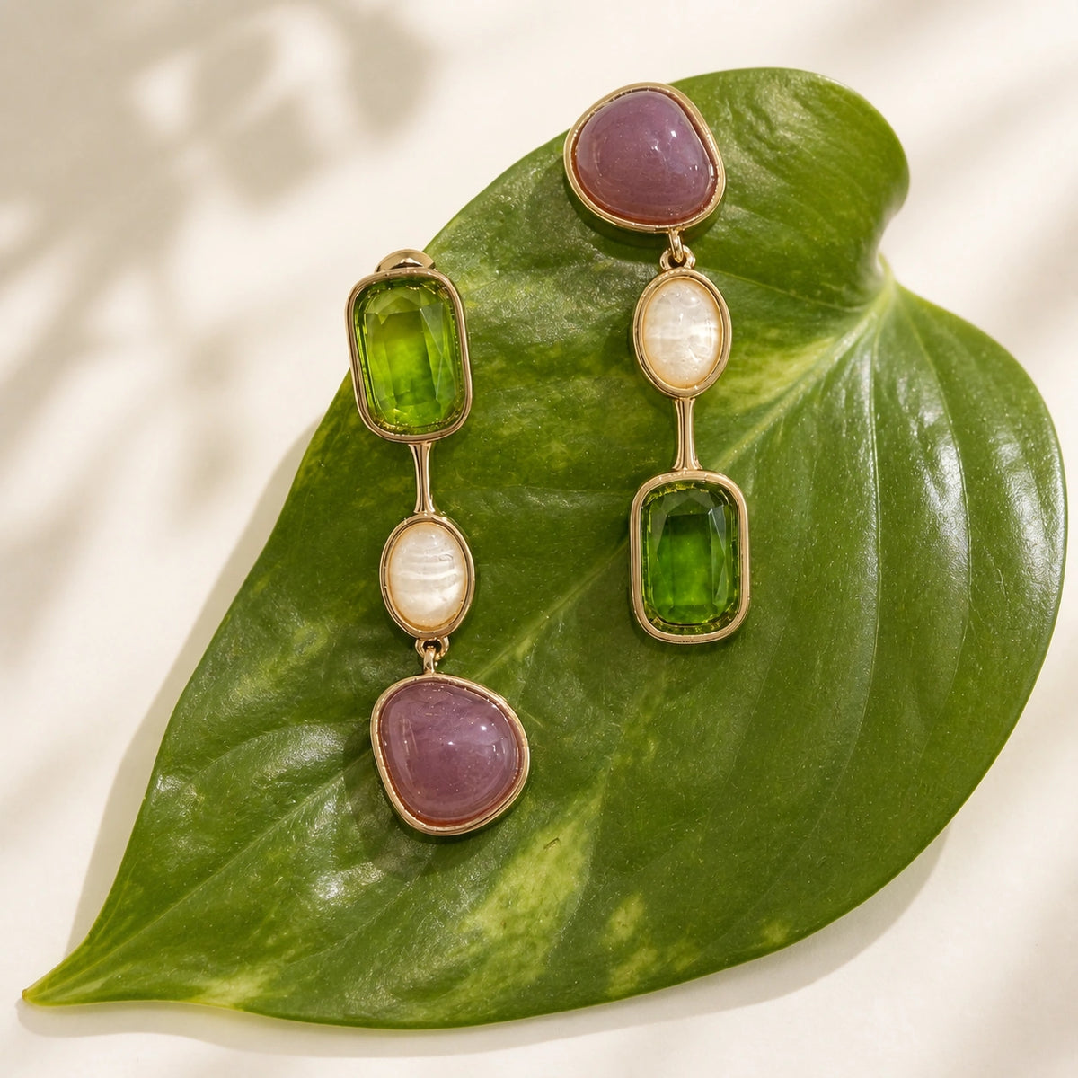 Green crystal drop earrings in gold styled on green leaf