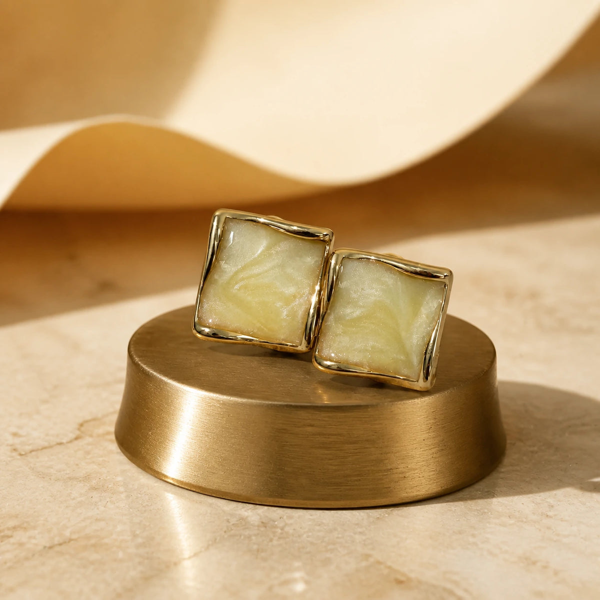 Butter yellow square stud earrings in gold styled on warm display stand