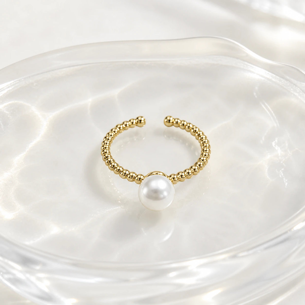 Minimal pearl ring in gold styled on white dish
