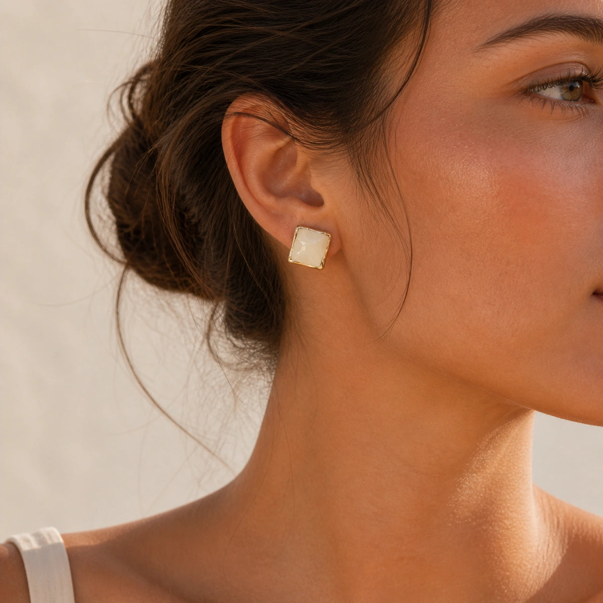 Cream square stud earrings in gold model wearing close-up