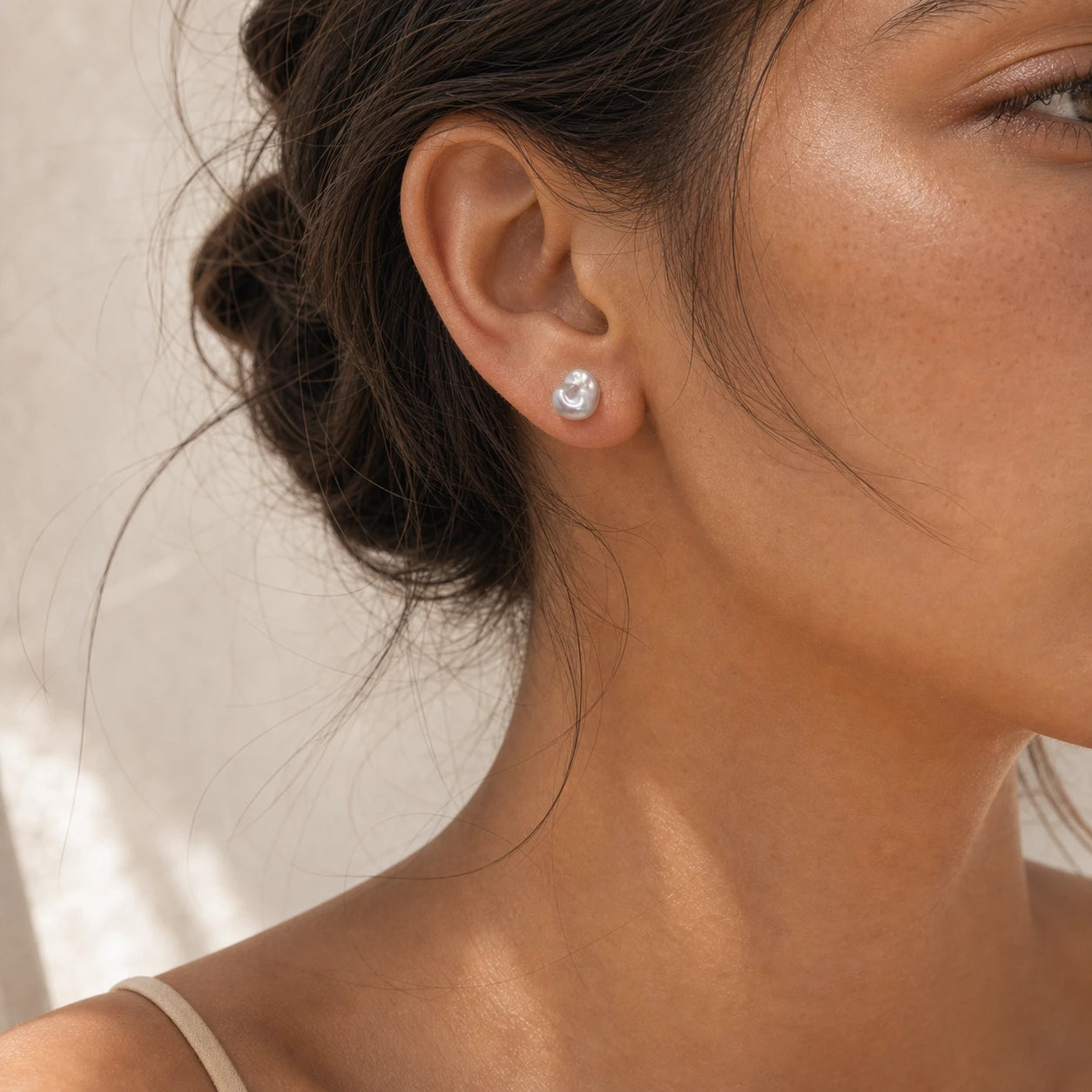 Blue baroque pearl stud earrings in silver worn close-up.