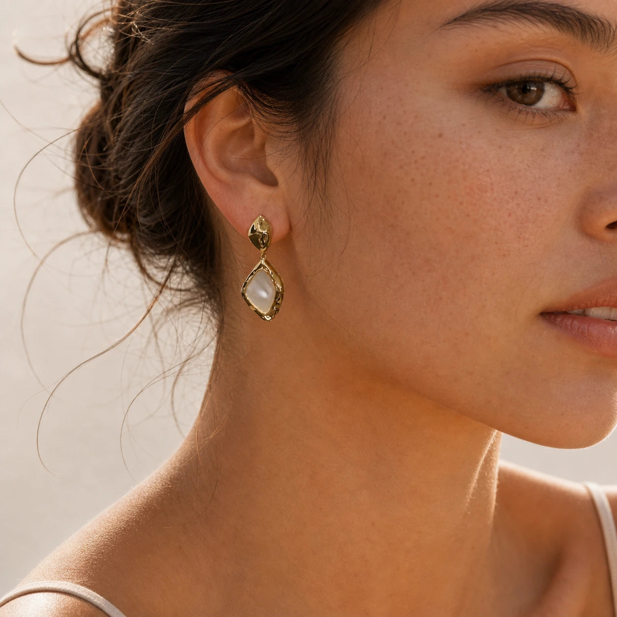 Square mother-of-pearl drop earrings in gold worn close-up