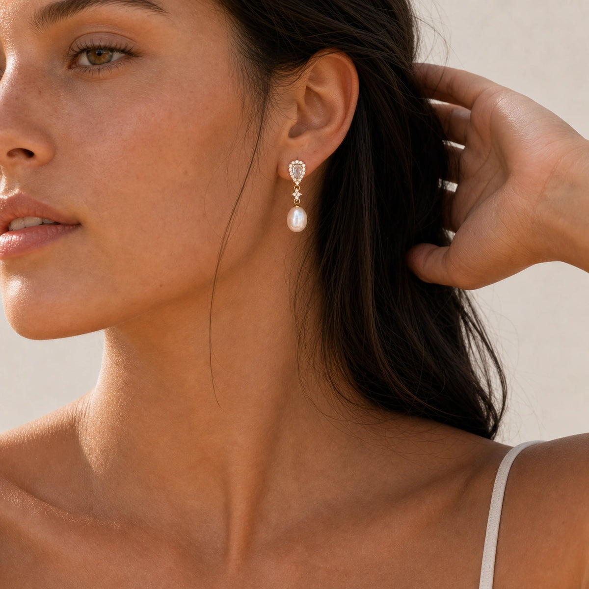 Crystal pearl teardrop earrings in gold model wearing close-up