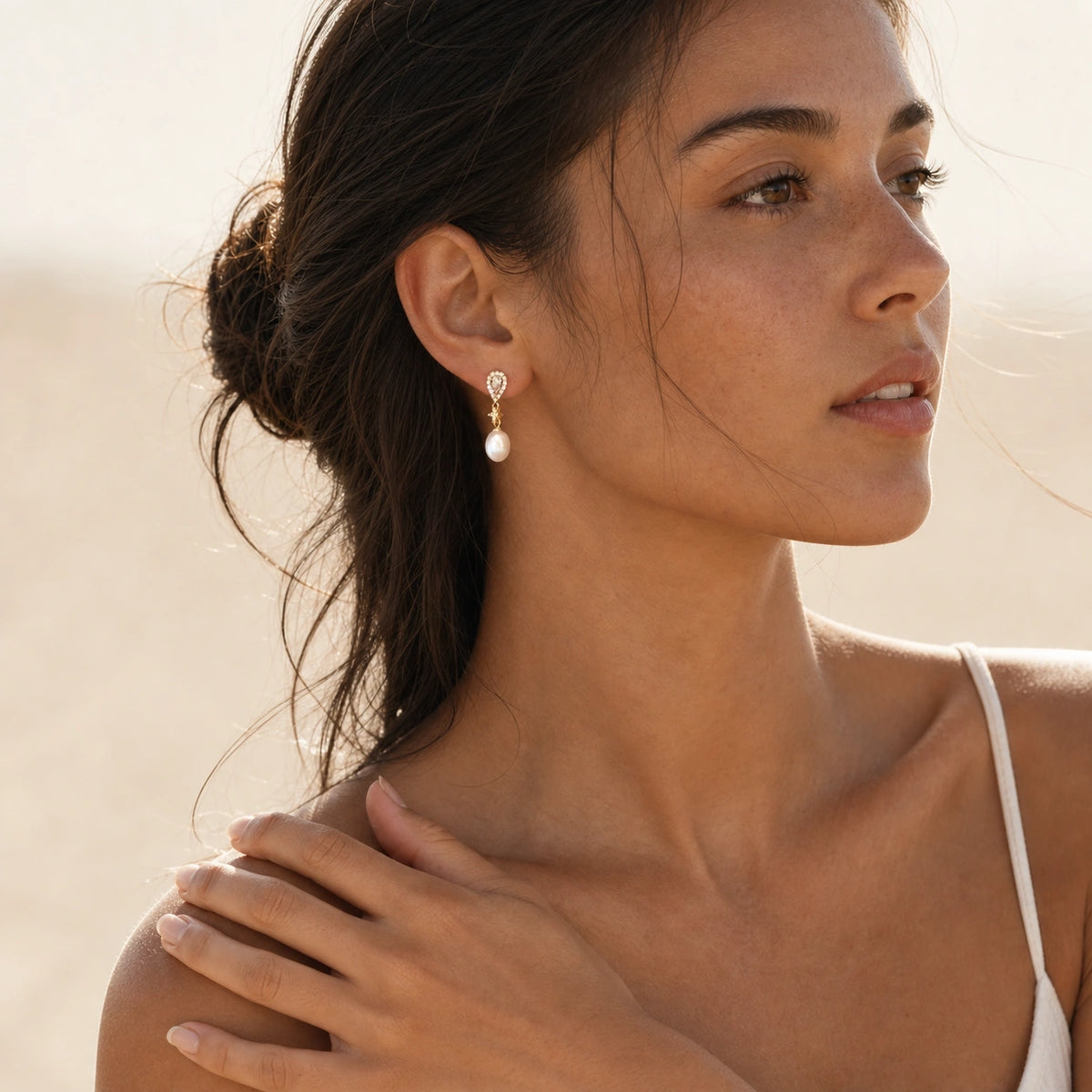 Crystal pearl teardrop earrings in gold worn close-up with pearl drop