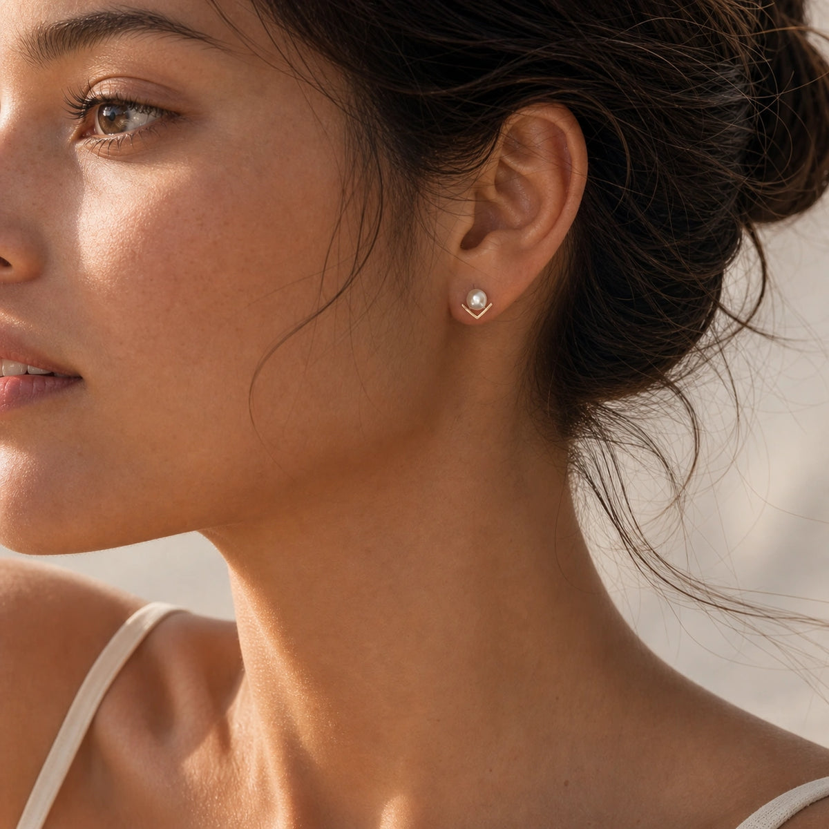 V-shaped pearl stud earrings worn close-up