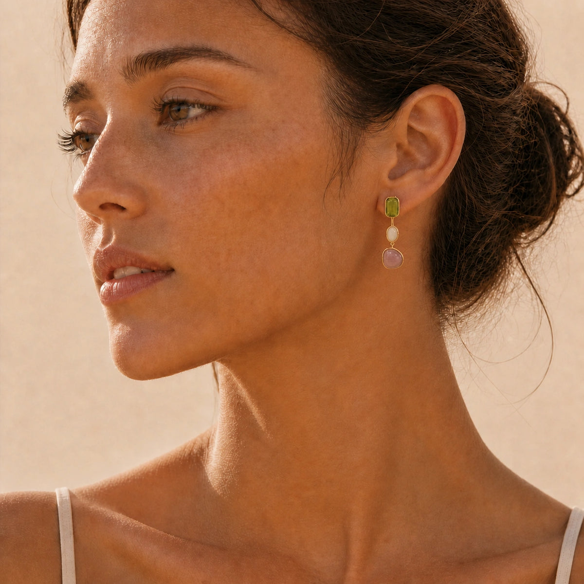 Green crystal drop earrings in gold worn close-up