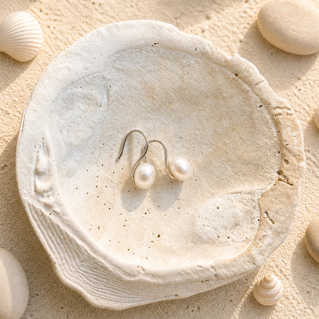 925 sterling silver freshwater pearl hook earrings displayed on a shell-textured plate.