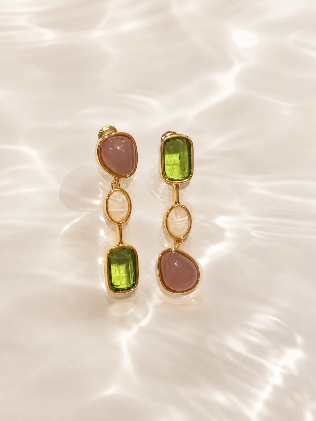Close-up of green stone drop earrings in Gold-plated brass with 925 sterling silver hooks.
