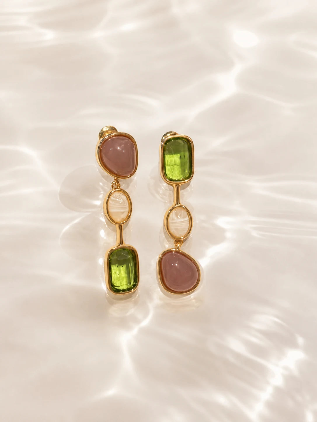 Close-up of green stone drop earrings in Gold-plated brass with 925 sterling silver hooks.