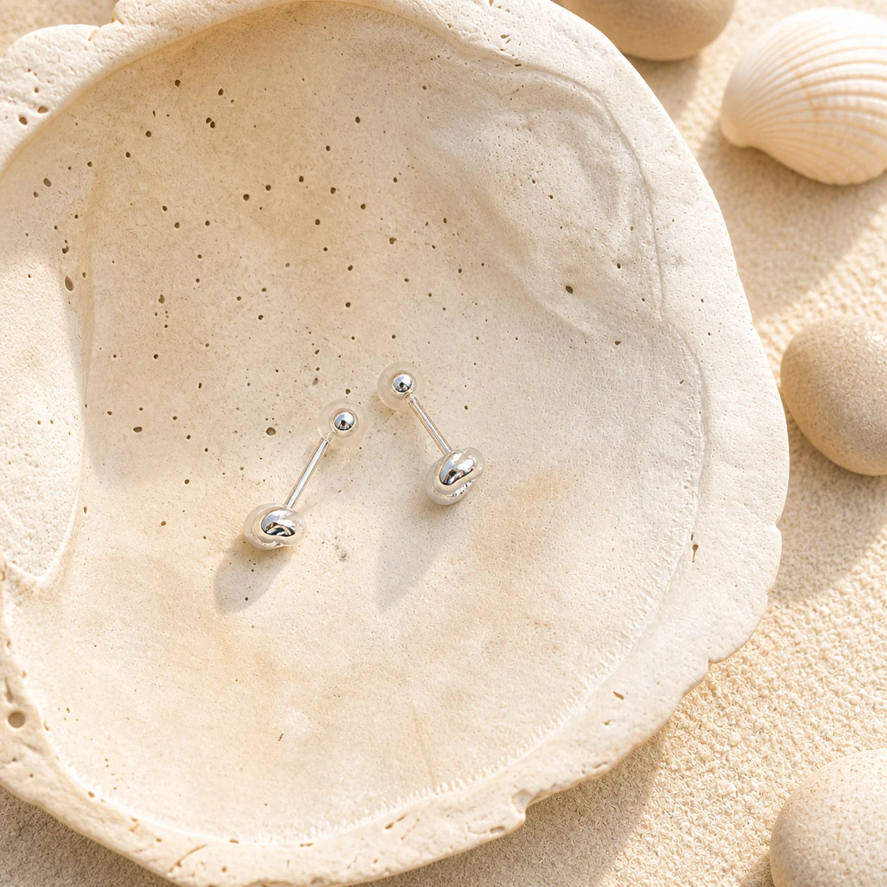 Knot Stud Earrings in 925 sterling silver displayed in a product styling scene.