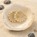 Mini Pearl Huggie Earrings in Gold-plated brass with 925 sterling silver posts displayed in a product styling scene.