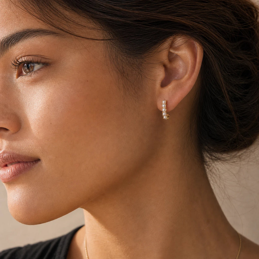 Close-up of mini pearl huggie earrings in Gold-plated brass with 925 sterling silver posts.