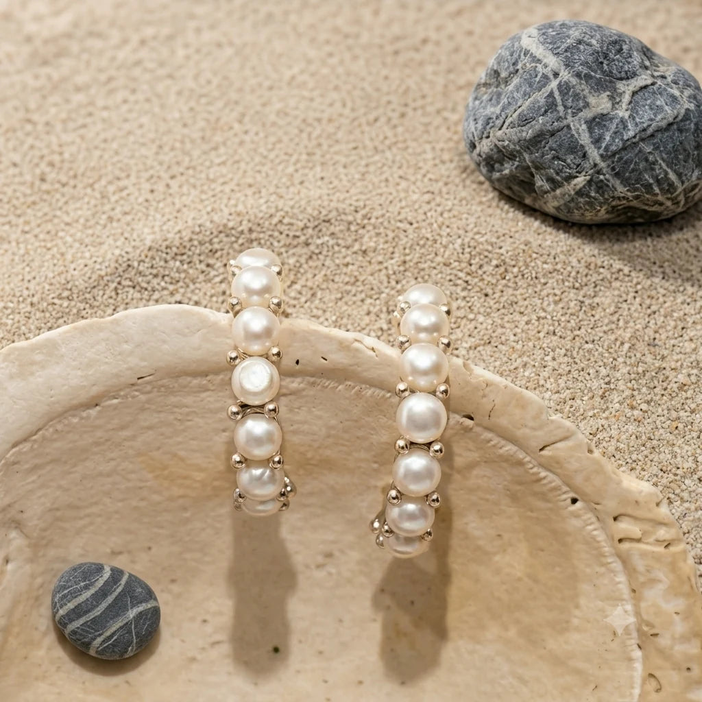Close-up of mini pearl huggie earrings in Rhodium-plated brass with 925 sterling silver posts.