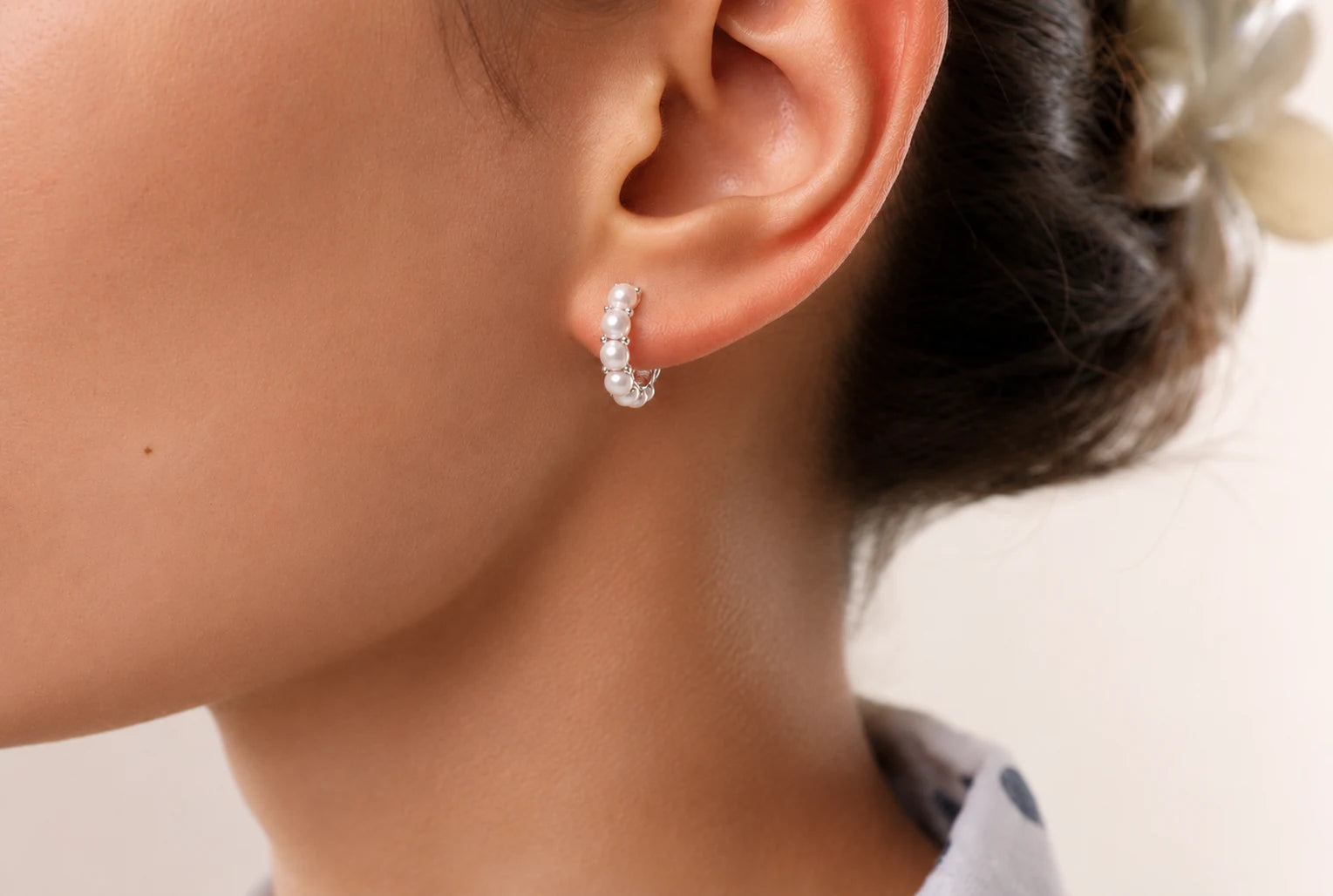 Close-up of mini pearl huggie earrings in Rhodium-plated brass with 925 sterling silver posts.