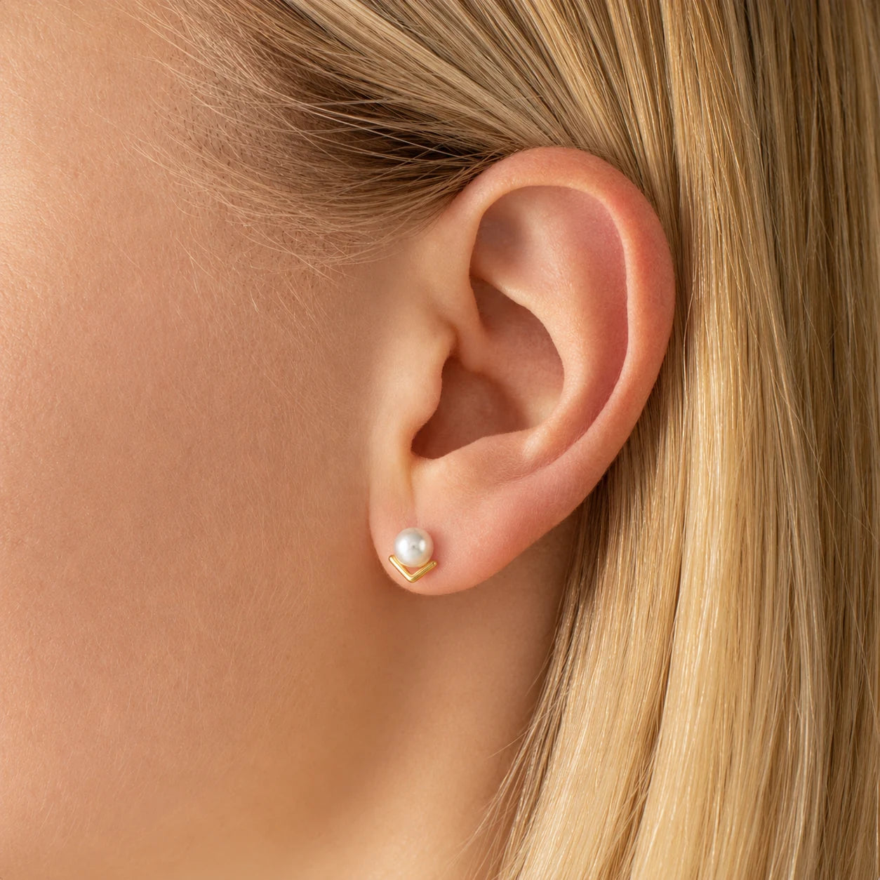 V-Shaped Pearl Stud Earrings in Gold-plated brass with 925 sterling silver posts displayed in a product styling scene.